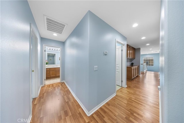 corridor featuring light wood-type flooring, baseboards, and recessed lighting