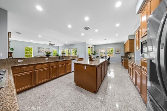 kitchen featuring appliances with stainless steel finishes, recessed lighting, brown cabinetry, a sink, and plenty of natural light