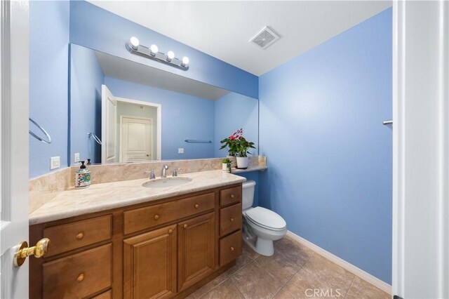 bathroom featuring toilet, vanity, tile patterned floors, and baseboards