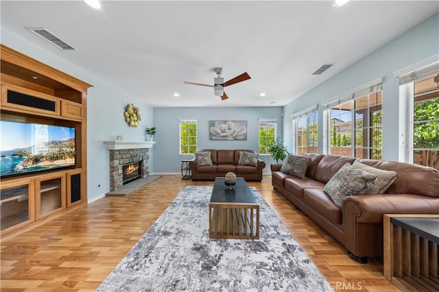 living area featuring recessed lighting, light wood finished floors, a stone fireplace, a ceiling fan, and baseboards