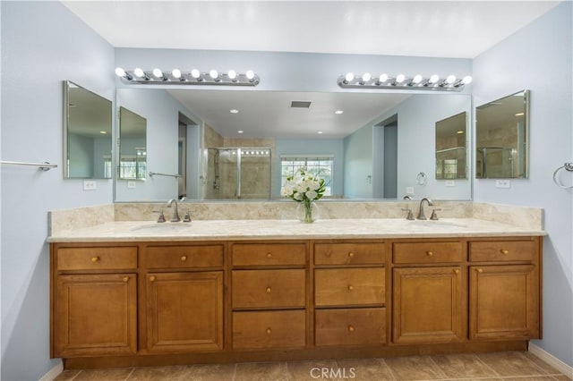 full bath with a shower stall, double vanity, and baseboards