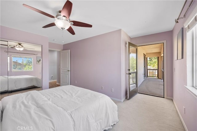bedroom featuring light carpet, multiple windows, baseboards, and a ceiling fan