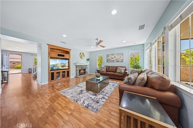 living room featuring light wood-style floors, ceiling fan, recessed lighting, a fireplace, and baseboards