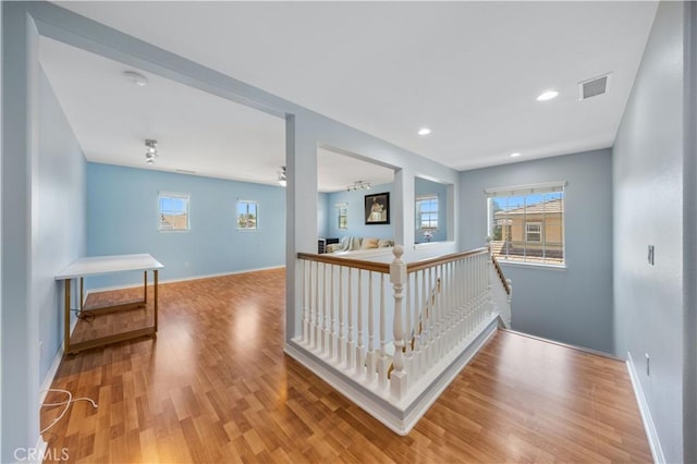 hall with wood finished floors, healthy amount of natural light, an upstairs landing, and recessed lighting