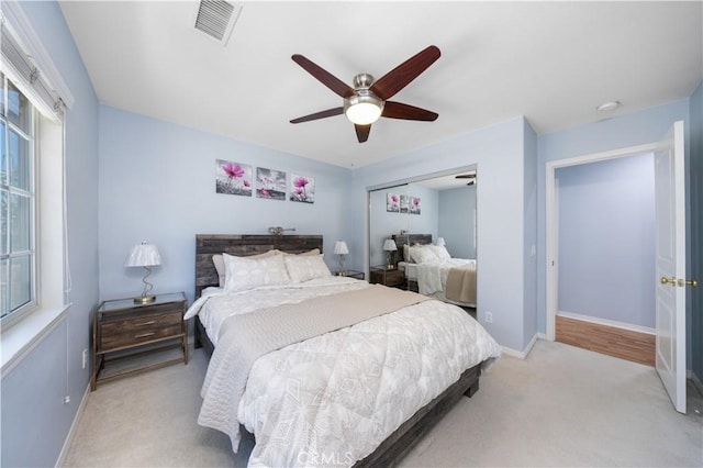 carpeted bedroom with multiple windows, baseboards, a ceiling fan, and a closet