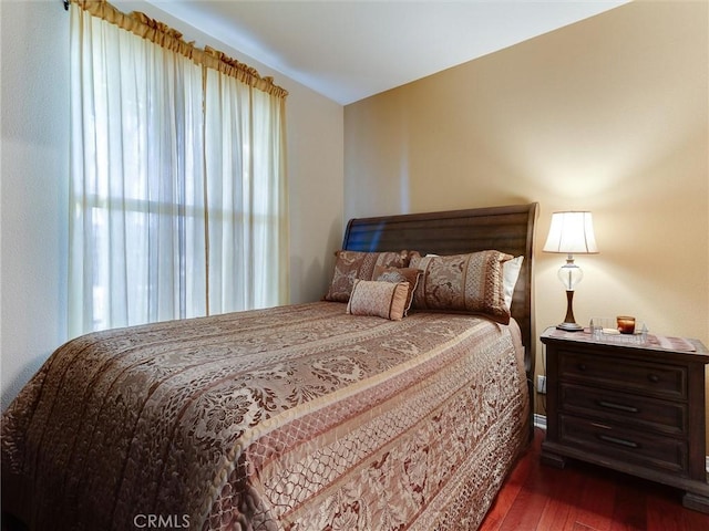 bedroom with multiple windows and dark wood finished floors