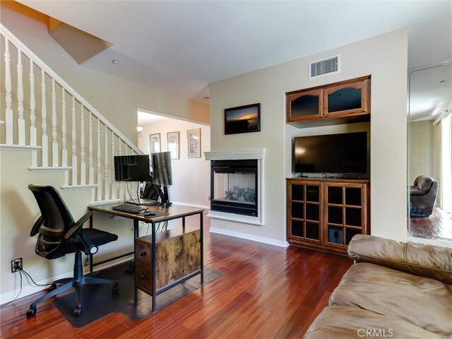 office area with wood finished floors, a multi sided fireplace, and baseboards