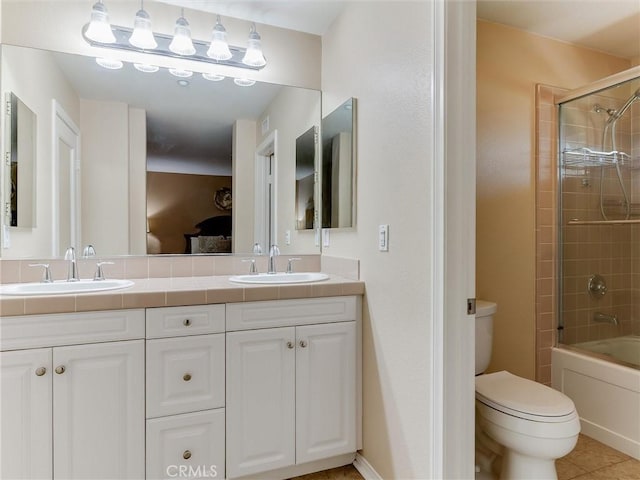 ensuite bathroom with toilet, double vanity, tile patterned flooring, and enclosed tub / shower combo