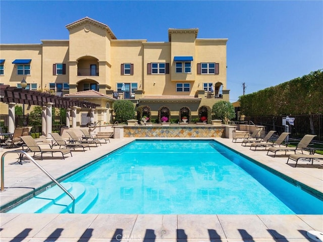 community pool featuring fence, a patio area, and a pergola