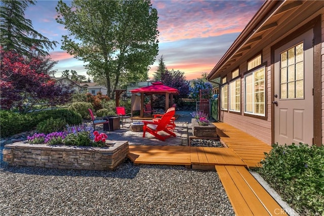 deck at dusk with a fire pit, a patio, and fence
