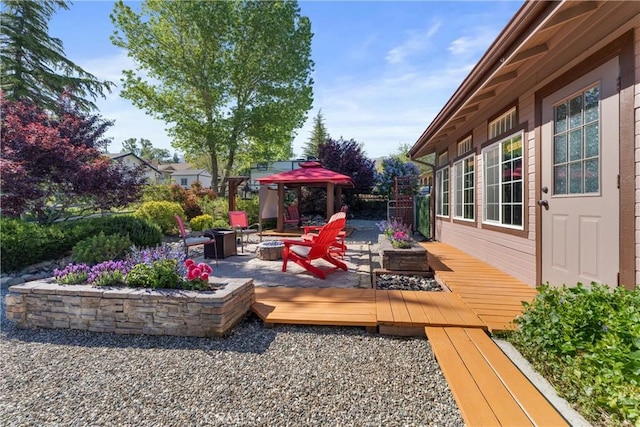 wooden terrace with a fire pit, a patio, and fence