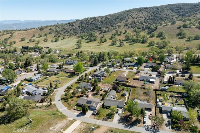 aerial view of property and surrounding area featuring nearby suburban area and a mountainous background
