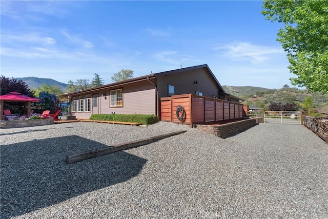view of side of property with a mountain view, a gate, and fence