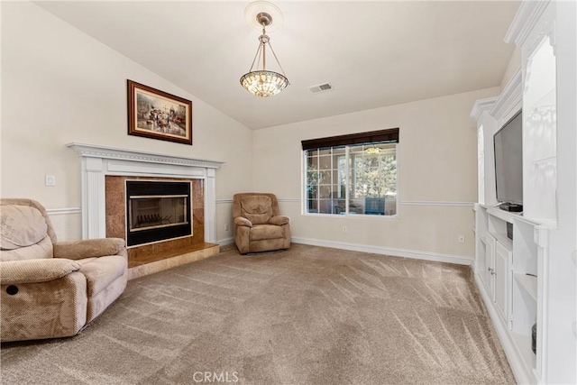 living area featuring carpet, a tiled fireplace, vaulted ceiling, baseboards, and a chandelier