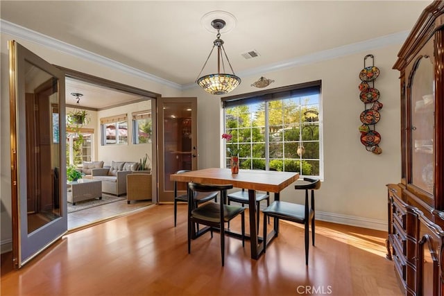 dining space with light wood finished floors, ornamental molding, and baseboards