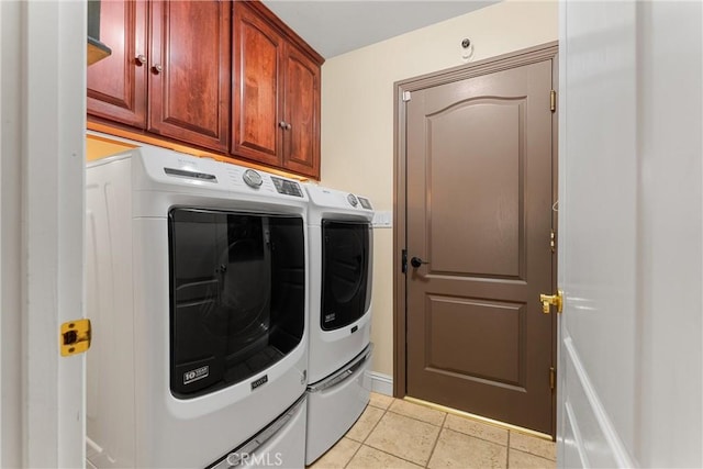 laundry area featuring washing machine and dryer, cabinet space, and light tile patterned floors