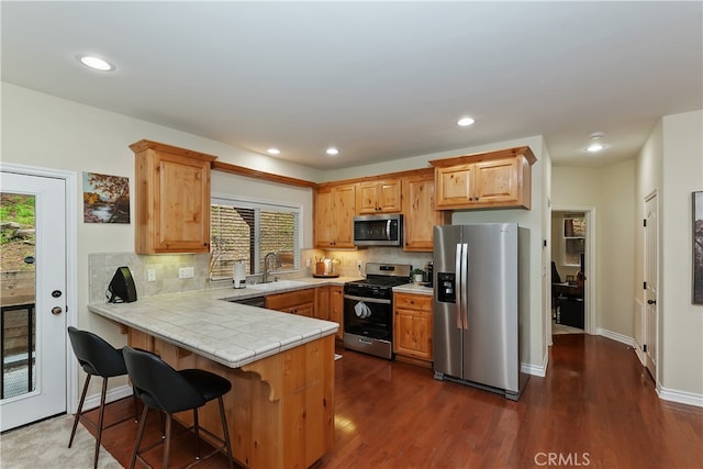 28589 Shenandoah Dr, Lake Arrowhead, CA 92352 - kitchen featuring appliances with stainless steel finishes, a peninsula, dark wood-style flooring, tile counters, and decorative backsplash