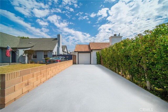 932 S Cloverdale Ave, Los Angeles, CA 90036 - view of side of property featuring a chimney, concrete driveway, stucco siding, a garage, and fence