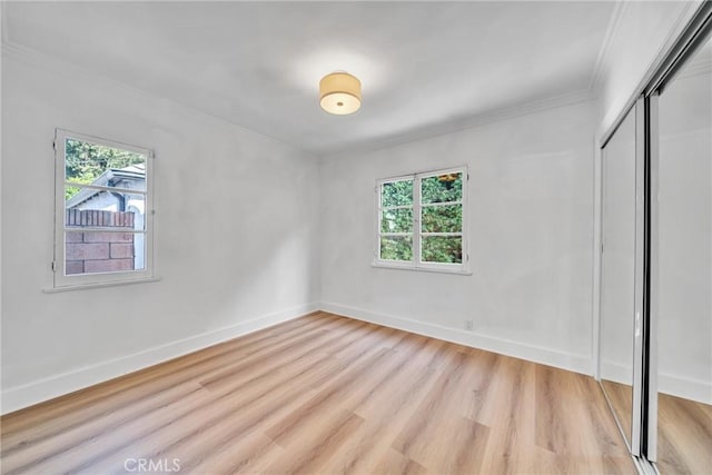 932 S Cloverdale Ave, Los Angeles, CA 90036 - unfurnished bedroom with multiple windows, a closet, crown molding, light wood-style floors, and baseboards