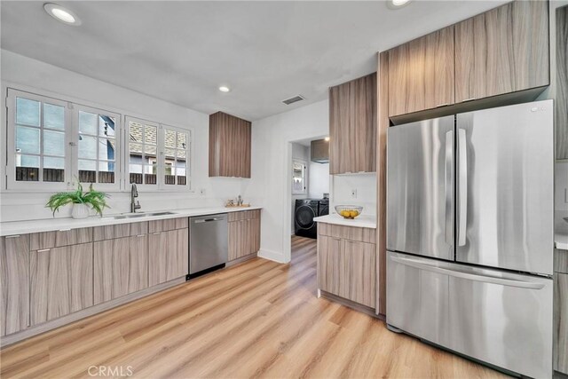 932 S Cloverdale Ave, Los Angeles, CA 90036 - kitchen with appliances with stainless steel finishes, a sink, washing machine and dryer, modern cabinets, and light wood-type flooring