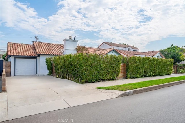 932 S Cloverdale Ave, Los Angeles, CA 90036 - mediterranean / spanish-style house featuring driveway, a tiled roof, an attached garage, stucco siding, and a chimney
