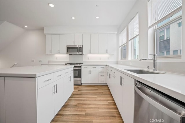 304 Placemark, Irvine, CA 92614 - kitchen featuring appliances with stainless steel finishes, a sink, recessed lighting, light wood-style floors, and white cabinets