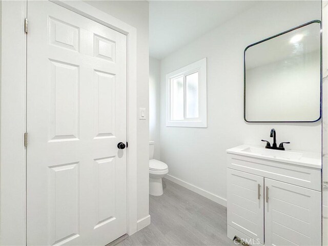 15811 S Tarrant Ave, Compton, CA 90220 - bathroom featuring toilet, baseboards, wood finished floors, and vanity