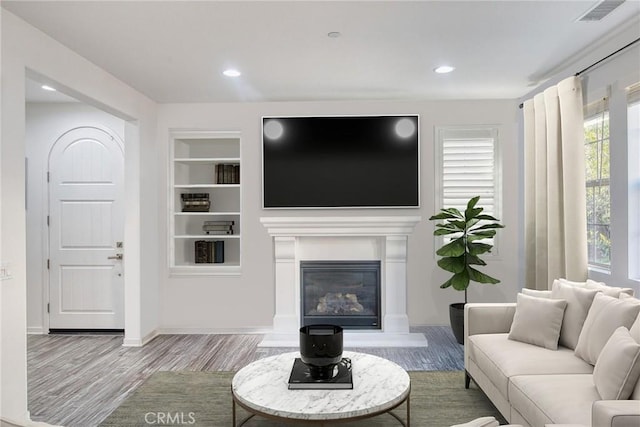 89 Baculo St, Rancho Mission Viejo, CA 92694 - living room featuring wood finished floors, built in shelves, a glass covered fireplace, and recessed lighting