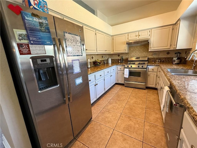 26490 Mapleridge Way, Moreno Valley, CA 92555 - kitchen with stainless steel appliances, a sink, under cabinet range hood, light tile patterned floors, and dark stone countertops