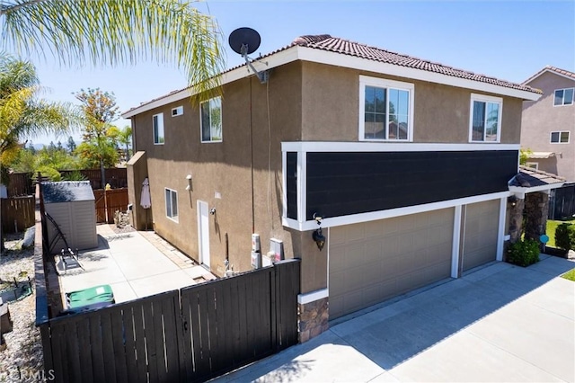 27917 Busman Rd, Murrieta, CA 92563 - view of side of home featuring stucco siding, a garage, driveway, and a tiled roof
