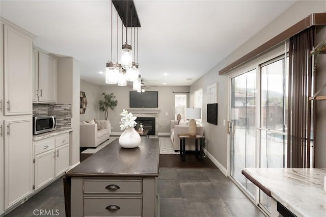 27917 Busman Rd, Murrieta, CA 92563 - kitchen with stainless steel microwave, a glass covered fireplace, open floor plan, white cabinets, and recessed lighting