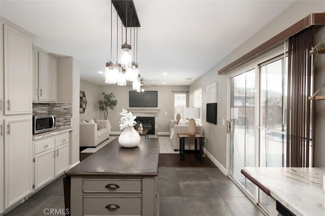 27917 Busman Rd, Murrieta, CA 92563 - kitchen with stainless steel microwave, a glass covered fireplace, open floor plan, white cabinetry, and recessed lighting