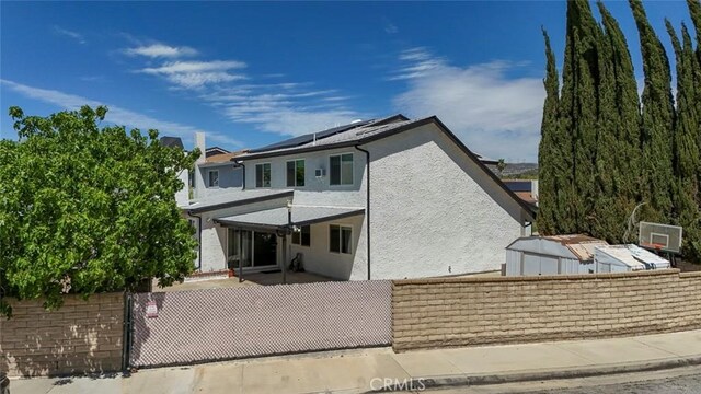 27533 Caraway Ln, Saugus, CA 91350 - back of property with a fenced front yard, solar panels, stucco siding, and a gate