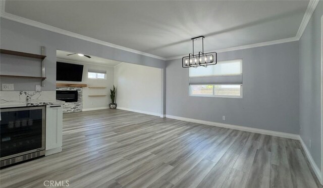 27533 Caraway Ln, Saugus, CA 91350 - unfurnished living room with wine cooler, light wood-type flooring, a stone fireplace, ornamental molding, and a chandelier