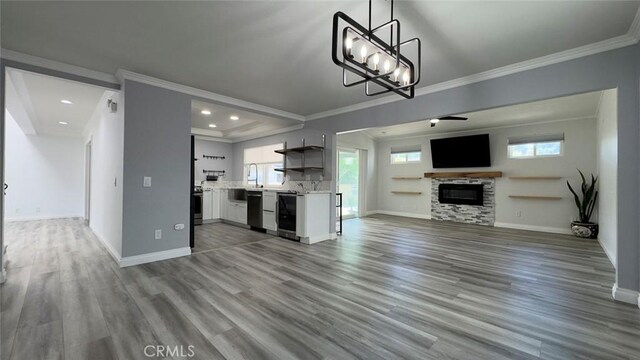 27533 Caraway Ln, Saugus, CA 91350 - unfurnished living room featuring crown molding, wood finished floors, a chandelier, a glass covered fireplace, and recessed lighting