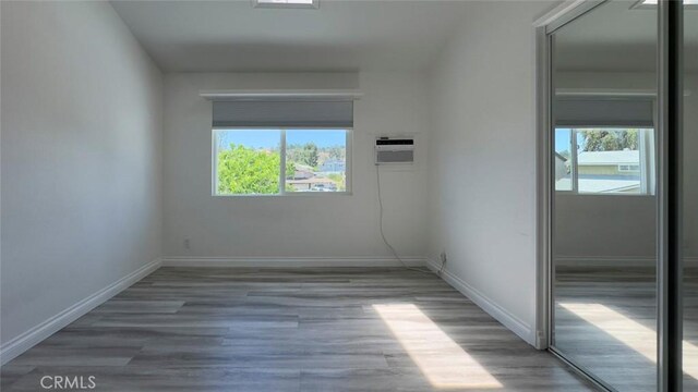 27533 Caraway Ln, Saugus, CA 91350 - unfurnished room with healthy amount of natural light, a wall mounted AC, and wood finished floors
