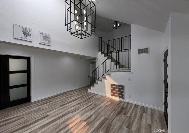 27533 Caraway Ln, Saugus, CA 91350 - unfurnished living room with a towering ceiling, a chandelier, wood finished floors, and stairs