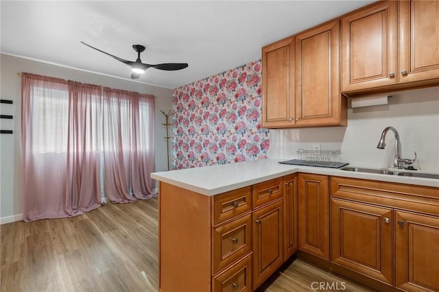 15015 Sherman Way Unit 314, Van Nuys, CA 91405 - kitchen with a sink, a ceiling fan, a peninsula, brown cabinets, and light countertops