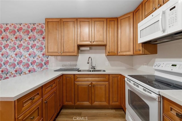 15015 Sherman Way Unit 314, Van Nuys, CA 91405 - kitchen with white appliances, a sink, light countertops, brown cabinets, and light wood-type flooring