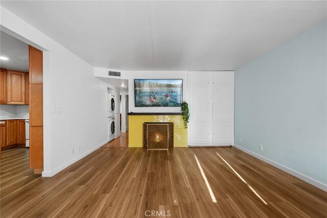 15015 Sherman Way Unit 314, Van Nuys, CA 91405 - unfurnished living room featuring stacked washer / drying machine, wood finished floors, a lit fireplace, and baseboards