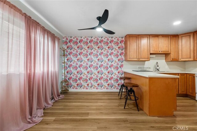 15015 Sherman Way Unit 314, Van Nuys, CA 91405 - kitchen featuring wallpapered walls, baseboards, light countertops, ceiling fan, and a kitchen breakfast bar