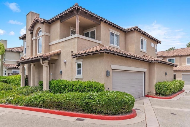 mediterranean / spanish home with stucco siding, a garage, a tile roof, and concrete driveway