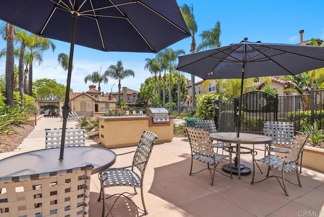 view of patio with exterior kitchen, outdoor dining space, fence, and a grill