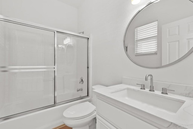 bathroom with toilet, combined bath / shower with glass door, and vanity