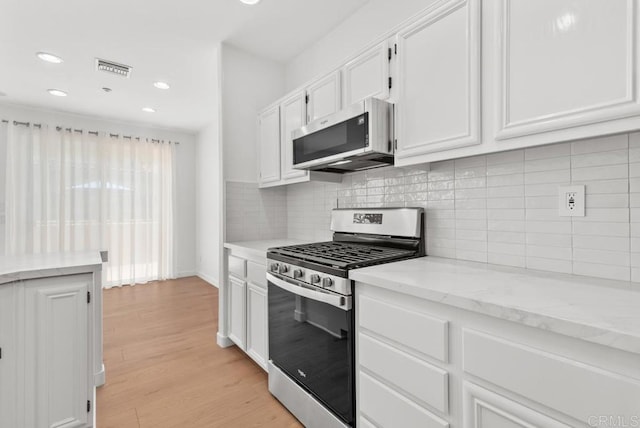 kitchen featuring stainless steel appliances, white cabinetry, light wood-style flooring, recessed lighting, and light stone counters