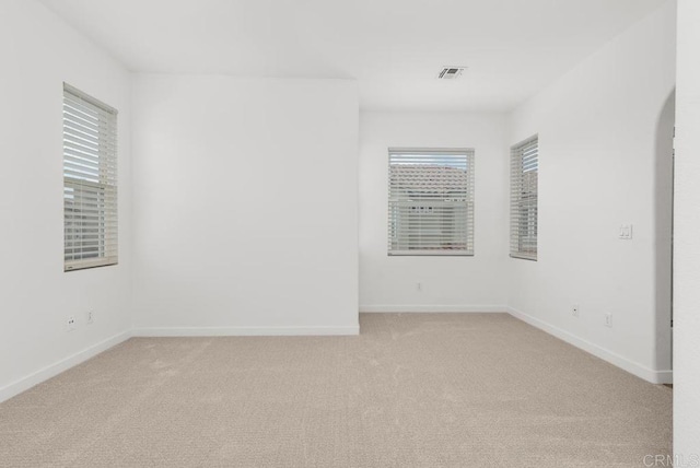unfurnished room with light carpet, baseboards, and arched walkways