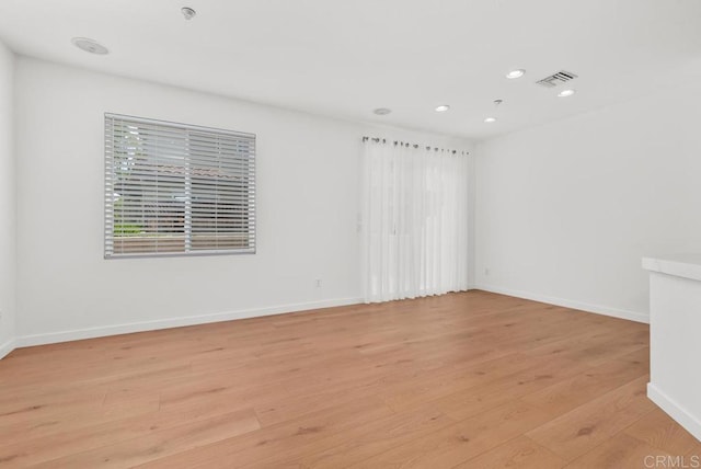 spare room with light wood-type flooring, recessed lighting, and baseboards