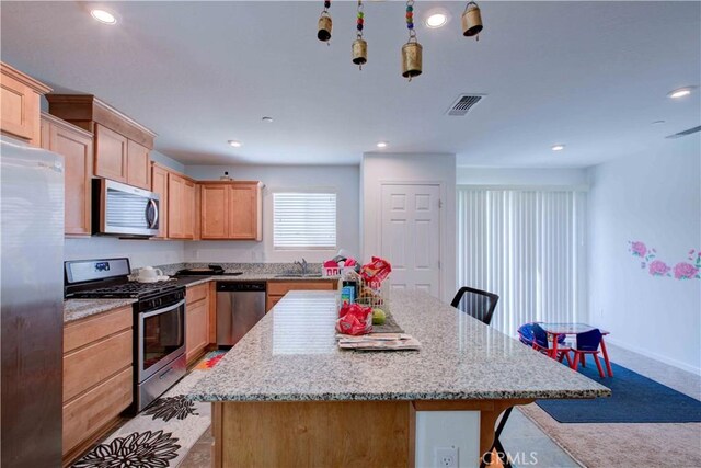 2045 Conadria Ave, Chowchilla, CA 93610 - kitchen featuring stainless steel appliances, a sink, a center island, light brown cabinetry, and a breakfast bar area