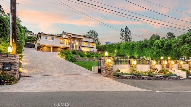 19151 Fowler Ave, North Tustin, CA 92705 - view of front of house featuring driveway, stone siding, an attached garage, a gate, and stucco siding