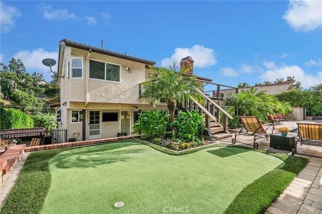 19151 Fowler Ave, North Tustin, CA 92705 - back of house featuring a putting area, stucco siding, stairs, a chimney, and a patio